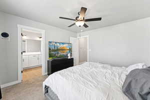 Bedroom featuring light colored carpet, ensuite bathroom, and ceiling fan