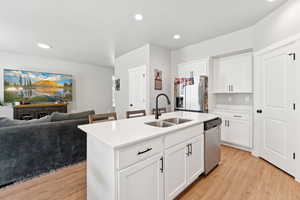 Kitchen with light wood-type flooring, appliances with stainless steel finishes, open floor plan, recessed lighting, and light countertops