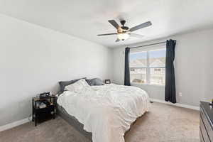 Bedroom with light colored carpet, a textured ceiling, and ceiling fan