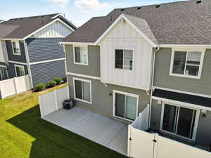 Rear view of property featuring roof with shingles, board and batten siding, and a patio