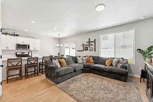 Living area featuring light wood-type flooring, a chandelier, and recessed lighting