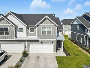 View of front facade featuring board and batten siding, roof with shingles, driveway, and an attached garage