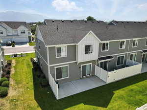 Back of property with roof with shingles, board and batten siding, and a patio area
