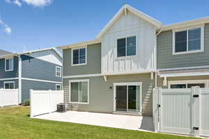 Back of house with board and batten siding, a patio area, and a gate