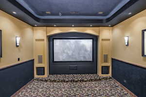 Home theater room with a tray ceiling, recessed lighting, and carpet flooring