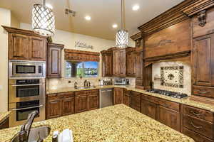 Kitchen featuring tasteful backsplash, stainless steel appliances, light stone countertops, hanging light fixtures, and recessed lighting