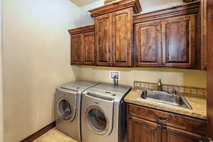 Laundry area featuring cabinet space, washer and clothes dryer, and light tile patterned floors