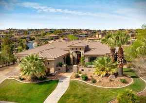 Mediterranean / spanish house featuring stucco siding, a tile roof, a front lawn, stone siding, and a residential view