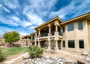 Back of property with a balcony, stucco siding, and a ceiling fan