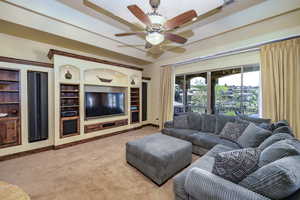 Living area with a ceiling fan, carpet, and built in shelves