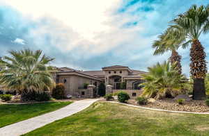 Mediterranean / spanish-style house featuring stone siding, stucco siding, a front yard, and a tile roof