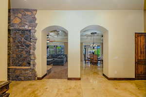 Foyer entrance with plenty of natural light, a ceiling fan, light tile patterned flooring, and arched walkways