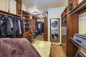 Washroom featuring estacked washer and dryer and carpet flooring