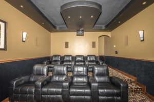 Cinema room featuring a wainscoted wall, a tray ceiling, and recessed lighting