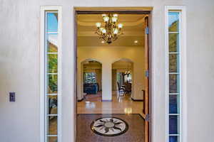 Foyer entrance with a chandelier, arched walkways, inlaid floor details, and recessed lighting