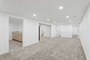 Finished below grade area featuring light carpet, recessed lighting, and bar