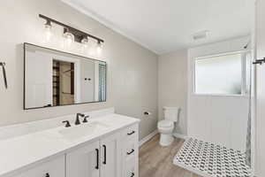 Bathroom with vanity, tiled shower, and wood finished floors