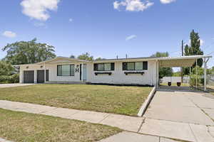 Ranch-style house featuring concrete driveway, brick siding, an attached carport, and an attached garage