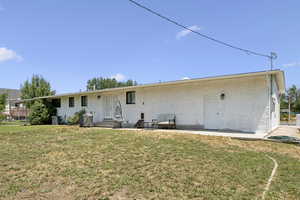 Back of house featuring a lawn, entry steps, brick siding, and a patio