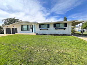 Ranch-style house featuring concrete driveway, a front lawn, and brick siding