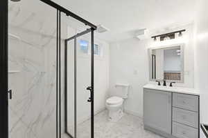 Full bath featuring a marble finish shower, vanity, and a textured ceiling