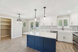 Kitchen with backsplash, light countertops, stainless steel appliances, white cabinets, and a center island