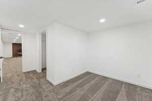 Carpeted empty room featuring baseboards and recessed lighting