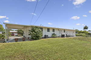 Rear view of property with an attached carport, a yard, and brick siding