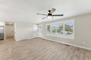 Unfurnished living room with light wood-style floors and a ceiling fan