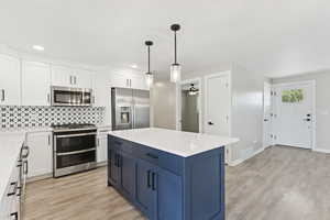 Kitchen with stainless steel appliances, white cabinetry, a ceiling fan, light wood finished floors, and recessed lighting