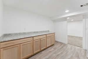 Kitchen featuring light brown cabinets, light wood-style flooring, light countertops, and recessed lighting