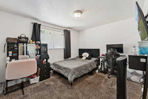 Bedroom with carpet floors, a textured ceiling, and a desk