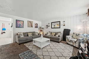 Carpeted living room featuring a textured ceiling and tile patterned floors