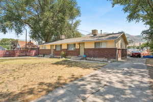 Single story home with brick siding, driveway, a chimney, and a mountain view