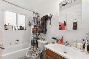 Full bath with vanity, shower / bath combo, and a textured wall