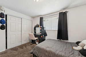 Carpeted bedroom featuring a textured ceiling and a closet