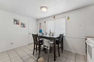 Dining area with a textured ceiling, wainscoting, and light tile patterned floors