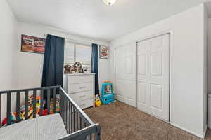 Bedroom featuring carpet flooring, a textured ceiling, and a closet