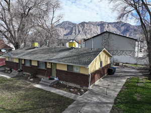View of front of property with brick siding, a mountain view, roof with shingles, and driveway