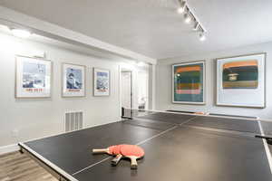 Game room with a textured ceiling and light wood finished floors
