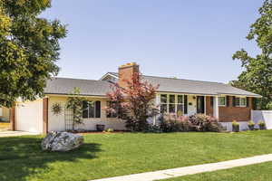 Ranch-style home with a front yard, roof with shingles, and brick siding