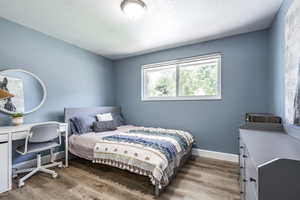 Bedroom with light wood-style flooring, an office area, and a textured ceiling