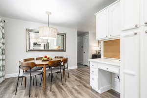 Dining area featuring light wood-style floors, built in desk, and a chandelier