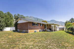 Rear view of property with a fenced backyard, brick siding, a mountain view, and a patio
