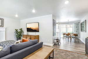 Living room with light wood-type flooring, a textured ceiling, recessed lighting, and a chandelier