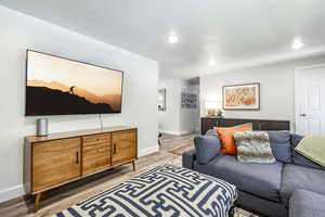 Living room with light wood-type flooring, a textured ceiling, and recessed lighting