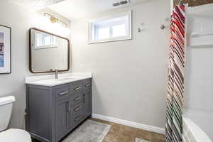 Full bath with vanity, shower / bath combo with shower curtain, light tile patterned floors, and a textured ceiling