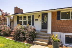 Doorway to property with a chimney and brick siding