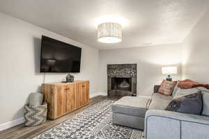 Living room featuring a textured ceiling, wood finished floors, and a tile fireplace