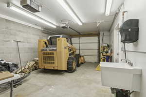 Roomy tandem garage with utility sink open into huge storage area with 1/2 bath.